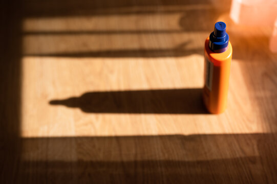 Sun Lotion Bottle On Wooden Floor Under Pleasant Afternoon Sunlight, Making Beautiful Shadow