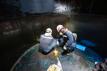 Male two worker inspection scan tank of rust thickness bottom plate