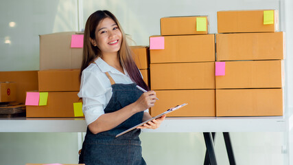 Portrait of Starting small businesses SME owners female entrepreneurs working, box and check online orders to prepare to pack the boxes, sell to customers, sme business ideas online.