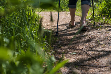Female legs with Nordic walking sticks, outdoors. Concept of a healthy lifestyle.