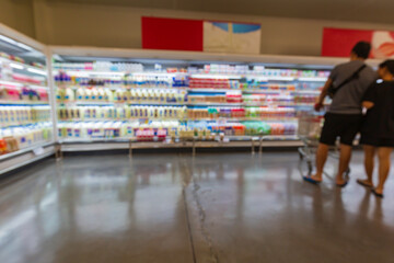 Defocused blur of male and female cart  buying milk in supermarket