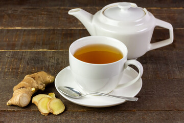 Ginger tea in white ceramic cup and fresh ginger and sliced on wooden background. The scientific name is zingiber officinale. Herbs for health care concept.
