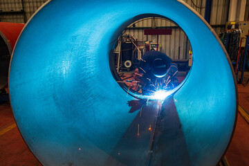 Male worker wearing protective clothing and repair welding industrial construction oil and gas or pipeline inside confined spaces.