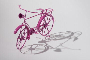 Small toy pink bike with shadow. Isolated on white background. Text space for greeting on World Cycling Day.