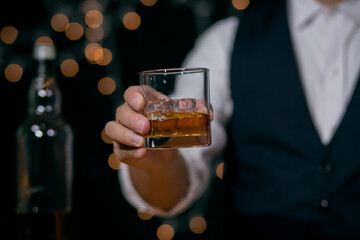Waitress man standing pours whiskey into a glass celebrate whiskey on a friendly party in restaurant