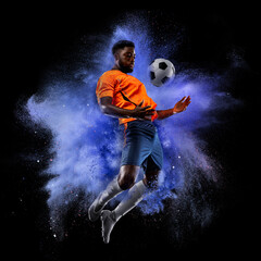 One young sportsman soccer football player in explosion of colored neon powder isolated on dark...