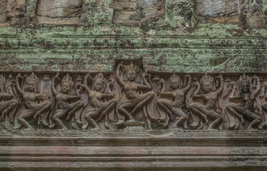 A carvings of lintels on a stone, women standing in line, showing dancing in verb raising right foot, flirting with both hands at Preach castle. Khan, Cambodia