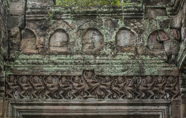 A carvings of lintels on a stone, women standing in line, showing dancing in verb raising right foot, flirting with both hands at Preach castle. Khan, Cambodia