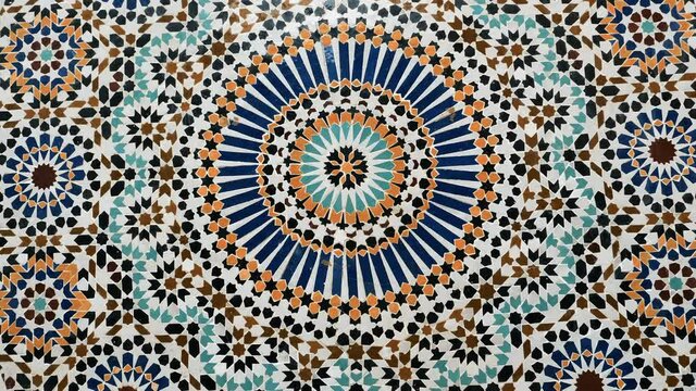 Colorful zellige pattern in traditional Islamic geometric design from a public fountain in Marrakech, Morocco. Made with natural colors from indigo, saffron, mint, kohl. Camera movement zooming in.