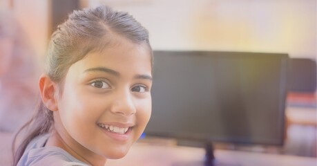 Composition of orange glow over happy school girl using computer