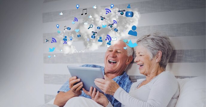 Composition of digital icons over happy senior couple using tablet in bed
