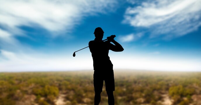 Composition of silhouette of male golf player over landscape and clouds on blue sky with copy space