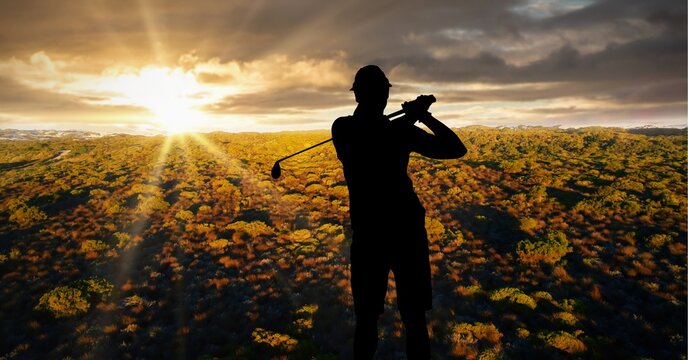 Composition of silhouette of male golf player over landscape and sunset
