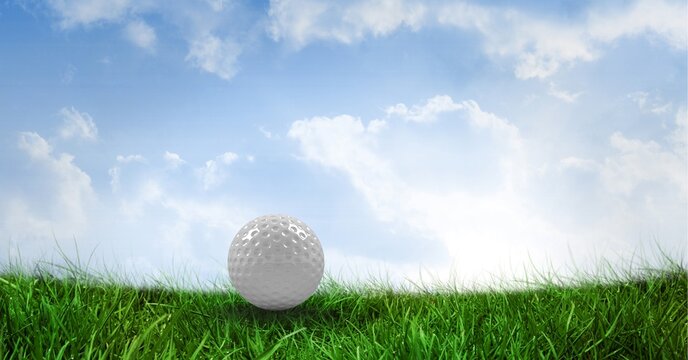 Composition of golf ball in grass with clouds and blue sky