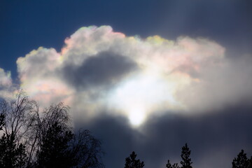 Sun behind rainbow colored clouds in April
