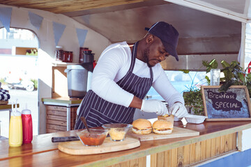 African american man in food truck preparing order with hamburgers on worktop