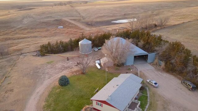 Aerial Panning Shot Of House And Garage Amidst Harvested Landscape In Field - Oakley, Kansas