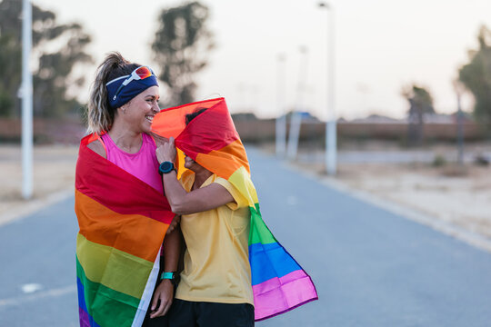 Lesbian couple with rainbow flag laughing. Gay Pride.Sport woman. LGBT community. concept of sexual freedom and racial diversity