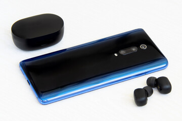 Blue phone with wireless headphones on white background
