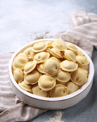 Russian and ukrainian cuisine. The national dish is dumplings in bowl. Dough with minced meat, flour, wooden spoon on a gray background.Background image, copy space