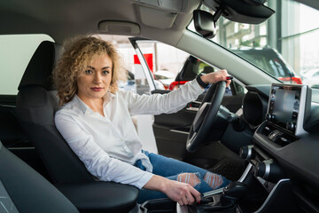 Confident woman sitting in new car at dealership