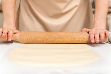 Cook rolls out the dough thinly with rolling pin. Process of making roll.