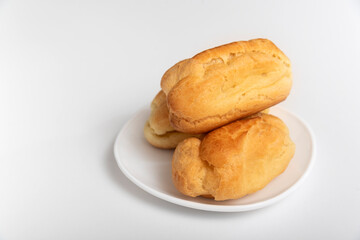 Profiteroles or eclairs without cream on white saucer. White background. Homemade baking