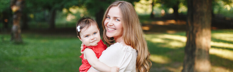 Mothers Day holiday. Smiling Caucasian mother and girl toddler daughter hugging in park. Mom...