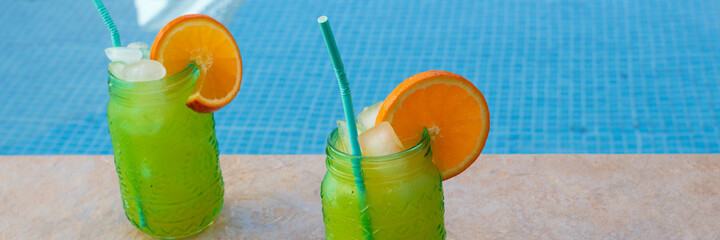 Cóctel con rodaja de naranja y mucho hielo en la piscina