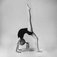 little gymnast demonstrates flexibility and balance in a gymnastic pose bridge with raised leg