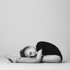 Girl gymnast doing bends to the legs, looking easily at the camera