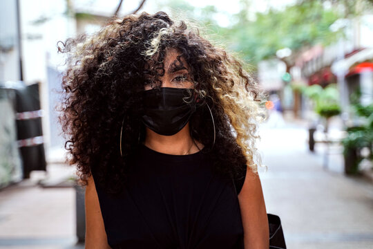 Afro Woman walking on the city street wearing surgical mask against disease coronavirus.