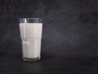 Glass of milk on dark background.