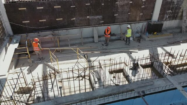 Large construction site of residential building with workers. Modern monolithic construction. Many different workers on the construction site. Construction of reinforced concrete structures