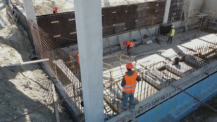 Naklejka premium Large construction site of residential building with workers. Modern monolithic construction. Many different workers on the construction site. Construction of reinforced concrete structures