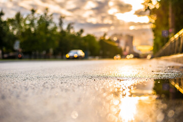 Sun after the rain in the city, view of the car with a level of puddles on the pavement