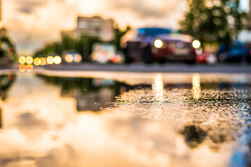 Sun after the rain in the city, view of the approaching car with a level of puddles on the pavement