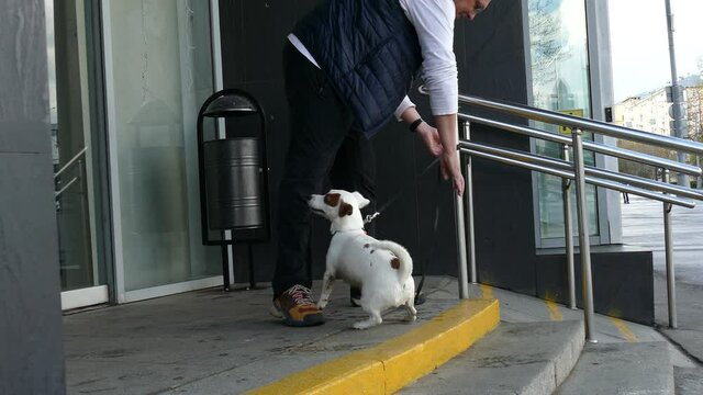 Man unties a dog that was tied near a store
