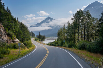 Camper travels along a curving highway in Alaska below mountains near Seward on a sunny afternoon - Powered by Adobe