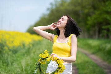 Naklejka na ściany i meble Portrait of a young beautiful girl in front of a yellow rapeseed field