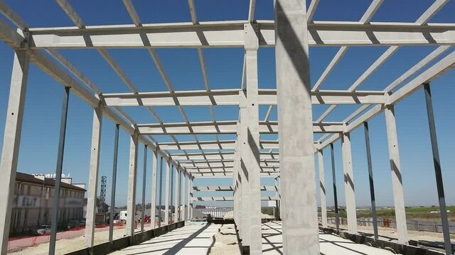 Reinforced Concrete Frame Of An Industrial Building. Camera Flight On A Construction Site. Beams With Steel Reinforcement From Above. Concrete Building Construction Industrial Site.