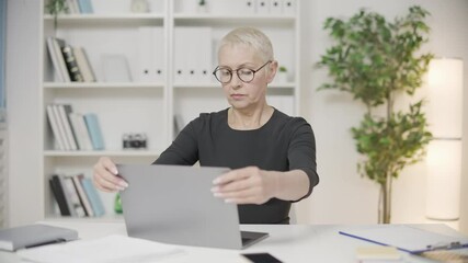Serious business woman finishing project on laptop in office, end of working day