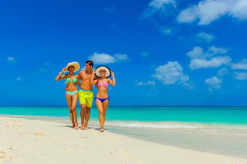 Three people, two woman and one male walking at the beach with beach hats, interracial, black 