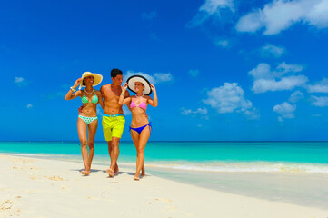 Three people, two woman and one male walking at the beach with beach hats, interracial, black 