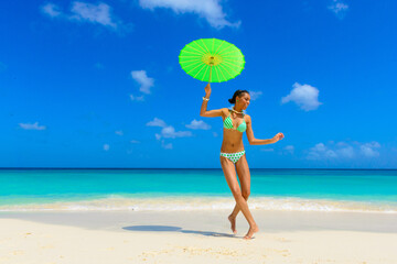 Girl having fun at the beach, standing on the seashore with green umbrella, interracial, black 