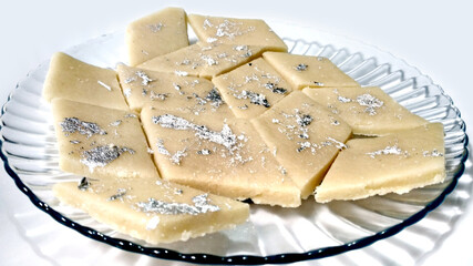 Kaju Katli is a Diamond shape Indian sweet made using cashew sugar and mava, served in a plate isolated on white background. selective focus