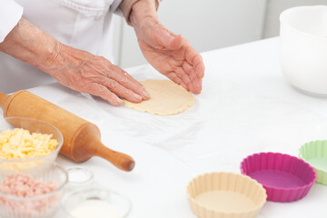Senior woman preparing dough for a delicious cheese and ham tartlet
