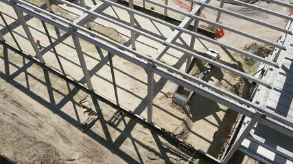 Reinforced Concrete Frame Of An Industrial Building. Camera Flight On A Construction Site. Beams With Steel Reinforcement. Dump Truck Unloads Sand in Construction. Aerial view. Unloading soil
