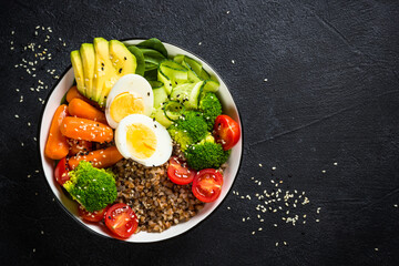 Obraz na płótnie Canvas Buddha bowl. Vegan food with buckwheat, egg, avocado and fresh vegetables at black. Top view with copy space. Healthy eating, diet menu.