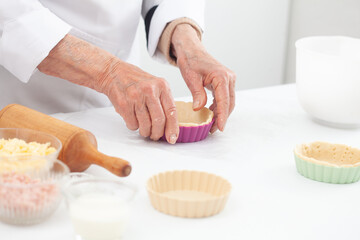 Senior woman preparing dough for a delicious cheese and ham tartlet